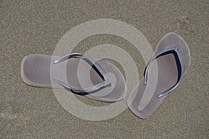 Brown pair of flip flop shoes on brown sand photo