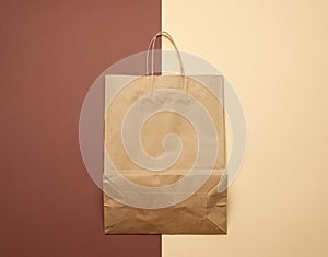 Brown paper bag with handles for shopping on a brown background