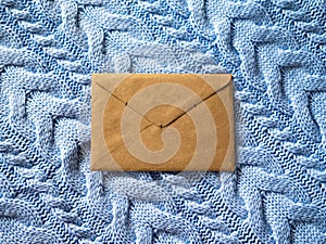 The brown paper envelope on the pale blue wool knitted background.