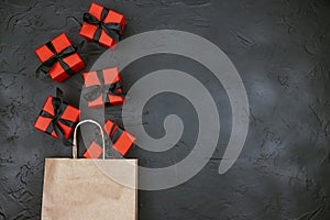 Brown paper shopping bag and red gift boxes with black ribbons on black  background