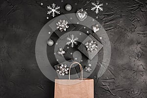 Brown paper shopping bag with silver Christmas decorations on a black background