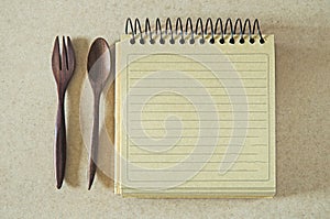 Brown paper spiral notebook and wood spoon and fork