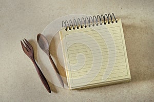 Brown paper spiral notebook and wood spoon and fork