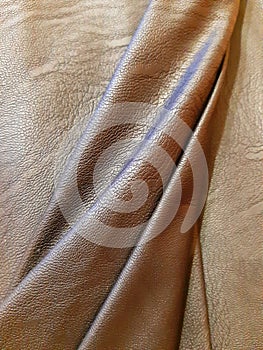 Brown pieces of leather surface with bend, fold. Background design, photography. Textile, fabric template, modern new