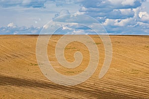 Brown plowed non-seeded field on a background of blue summer sky. sunny sky over an empty meadow. serenity, bliss. desktop