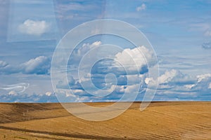 Brown plowed non-seeded field on a background of blue summer sky. sunny sky over an empty meadow. serenity, bliss. desktop