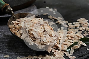 Brown Poha or Aval / flattened Rice flakes in a metal scoop, selective focus photo
