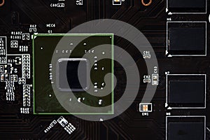 A brown printed circuit board with a processor chip and video memory strips. Electronic components on the graphics card