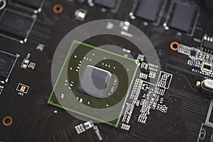 A brown printed circuit board with a processor chip and video memory strips. Electronic components on the graphics card