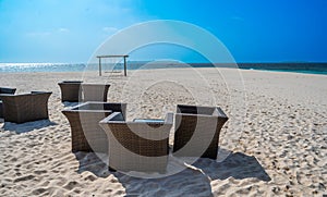 Brown rattan chairs on the beach. View of the sea and the island on the horizon