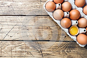 Brown raw eggs in factory packaging on rustic wooden background. Copy space
