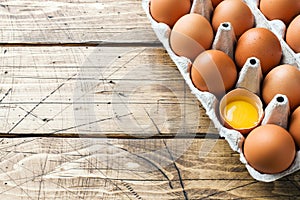 Brown raw eggs in factory packaging on rustic wooden background. Copy space