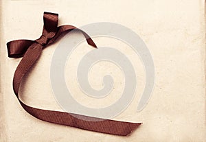 Brown ribbon over vintage gift old paper background