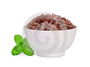 Brown rice in the white bowl with mint leaf isolated on white