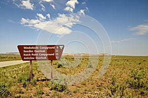 Brown road sign indicating the distance to different destination.