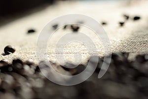 Brown roasted coffee beans are scattered on the burlap macro