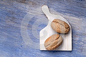 Brown rolls on a wooden chopping board isolated on blue table