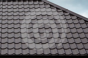 Brown roof tiles or shingles on house as background image. New overlapping brown classic style roofing material texture pattern o