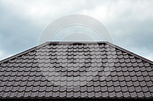 Brown roof tiles or shingles on house as background image. New overlapping brown classic style roofing material texture pattern o