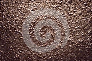 Brown rough concrete painted wall. Grunge background. Reflective on raggy surface. Dark texture with metallic gloss. Shiny stucco,