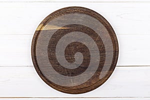 Brown round cutting board on a white wooden background. View from above