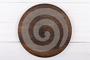 Brown round cutting board on a white wooden background. View from above