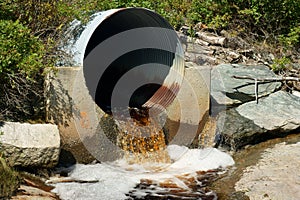Brown runoff water from rusted culvert photo