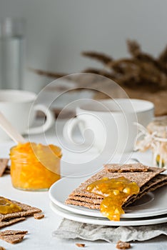 Brown rye crisp bread Swedish crackers with spread orange jam and cups of tea