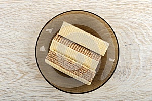 Brown saucer with wafers on wooden table. Top view