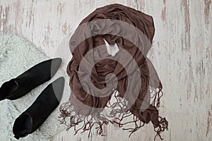 Brown scarf and black shoes on wooden background. Fashionable co