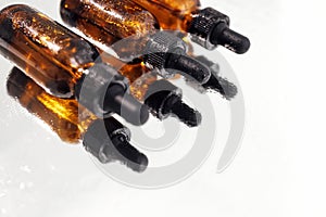 Brown serum or oil glass mock up three bottles with pipette on white background. Group of bottles with drops on them and their