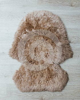 Brown sheepskin fur carpet on wooden floor