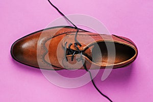 Brown shoes on a colored background with untied laces. Fashionable classic leather shoes. Men`s style. The view from the top