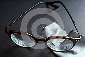 Brown shortsighted or nearsighted eyeglasses with microfibre cleaning cloths, On black background, Optical concept