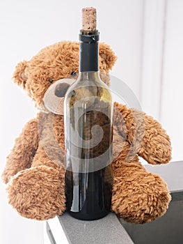 Brown soft bear, hugged to a bottle of red wine