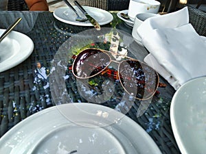 Brown spectacles on the table surrounded by white plates, cup and serbs photo