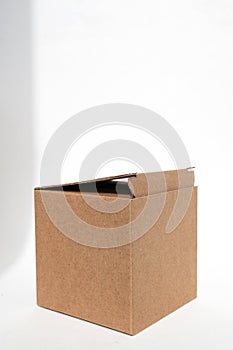 Brown square corrugated cardboard box on a white background. Added shadows, copy space