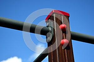 Brown stained wood post with steel exercise bar pipes bolted. red plastic cap