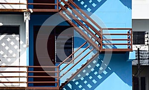 Brown steel fire escape staircase on blue wall outside the building
