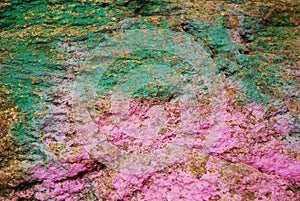 Brown stone painted with paint in pink and green. Rock background, texture. Pattern