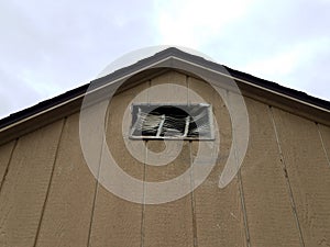 Brown storage shed building with damaged vent
