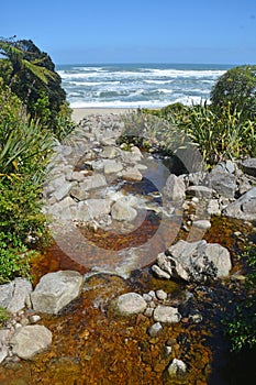 Brown Stream, caused by natural leaching of Nothofagus plants, at Scotts Beach, Heaphy Track, Karamea photo