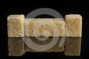 Brown sugar cube isolated on black glass