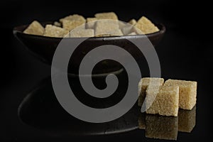 Brown sugar cube isolated on black glass