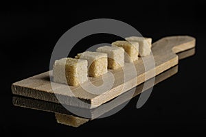 Brown sugar cube isolated on black glass