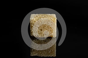Brown sugar cube isolated on black glass