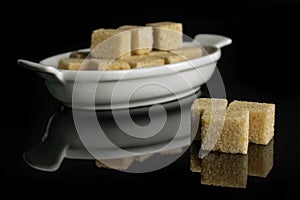 Brown sugar cube isolated on black glass