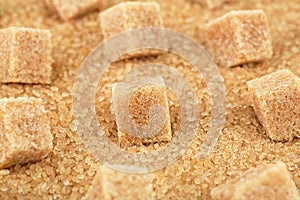 Brown sugar cubes on cane sugar crystals, close up.