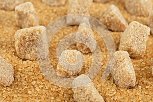 Brown sugar cubes on cane sugar crystals, close up. Demerara golden sugar