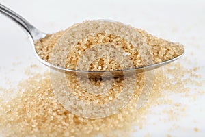 Brown sugar in spoon on white background